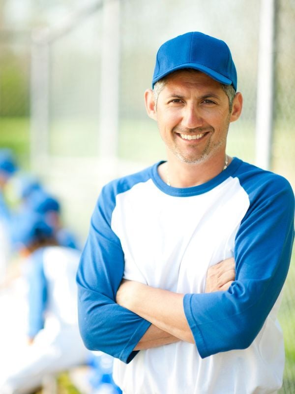 Coach wearing a blue cap and smiling