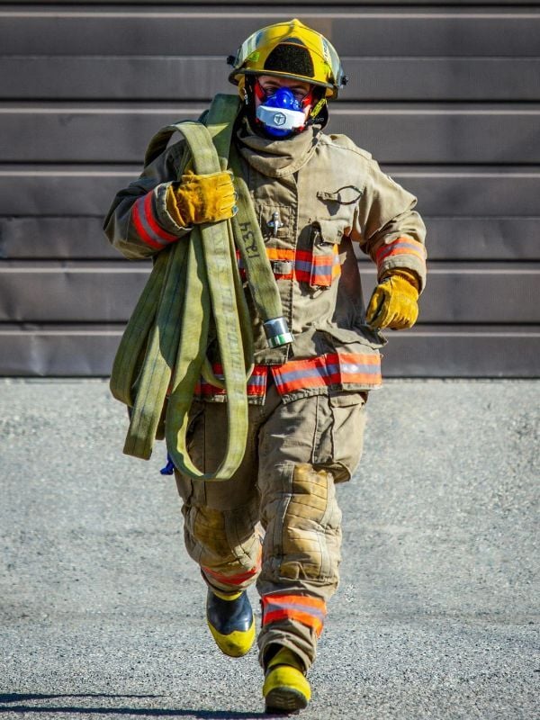 Firefighter in protective gear carrying a hose