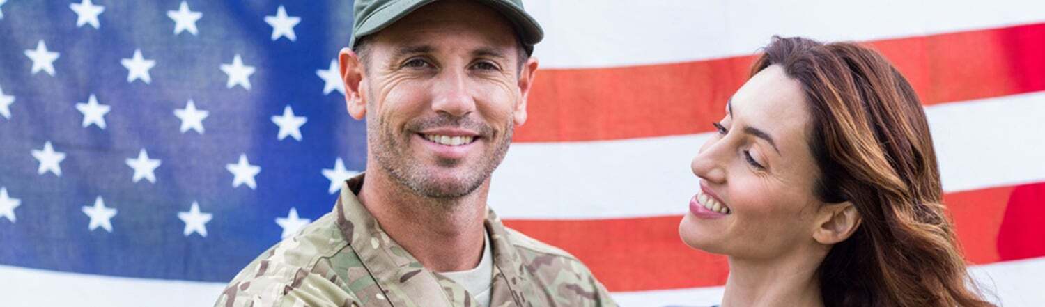 Service member and partner in front of an American flag