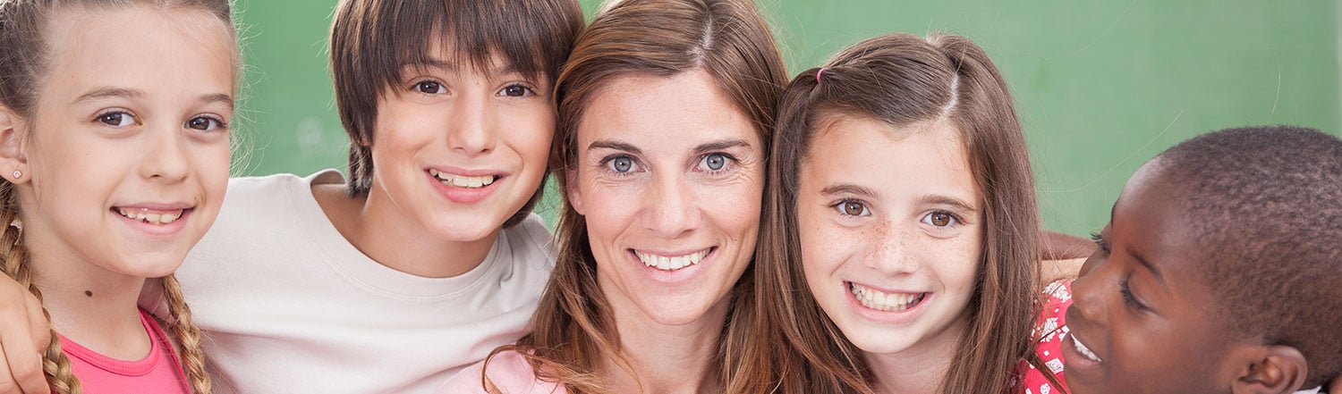 Teacher surrounded by smiling schoolchildren