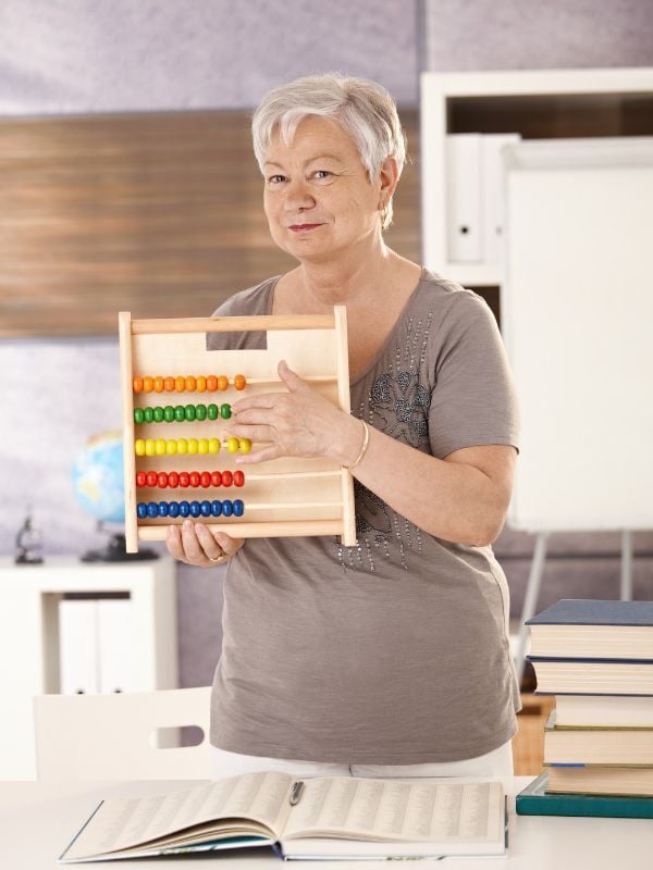 Experienced teacher holding an abacus in a classroom